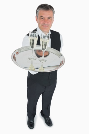 Waiter in suit serving glasses of champagne on silver trayの写真素材