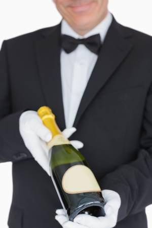Smiling waiter offering bottle of champagneの写真素材