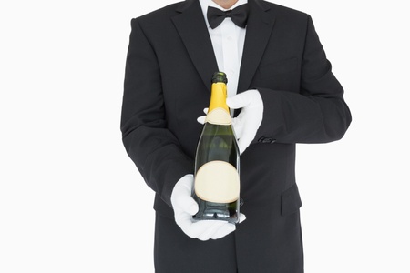 Waiter holding open champagne bottle on white backgroundの写真素材