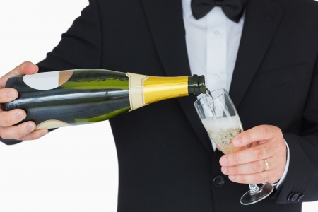 Well-dressed man pouring champagne into fluteの写真素材