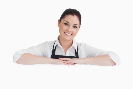 Smiling woman resting on her arms wearing apron on white background