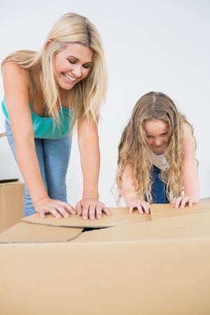 Mother and daughter laughing and closing moving boxesの写真素材
