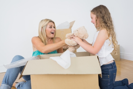 Mother and daughter unpackig teddy bear in new homeの写真素材