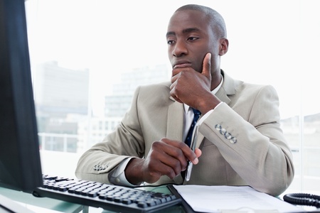 Serious entrepreneur while working with a computer in his officeの写真素材