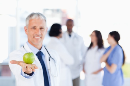 Smiling mature doctor holding an appleの写真素材
