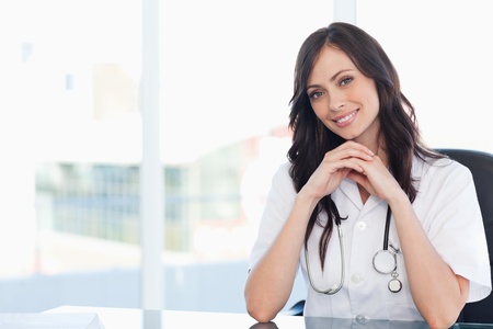 Nurse sitting at the desk with her hands crossed and leaning her head to the sideの写真素材