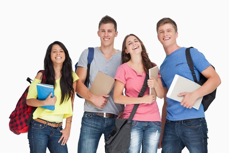 A laughing group of students with notepads and backpacks as they look at the cameraの写真素材