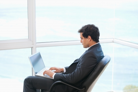 Man sitting on a chair while typing on a computer の写真素材
