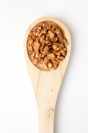 Wooden spoon with nuts against a white background