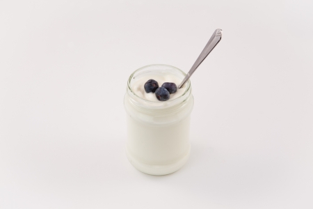 Pot of yoghurt with three blueberries against a white backgroundの写真素材