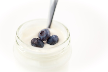 Close up of a pot of yoghurt with blueberries against a white backgroundの写真素材