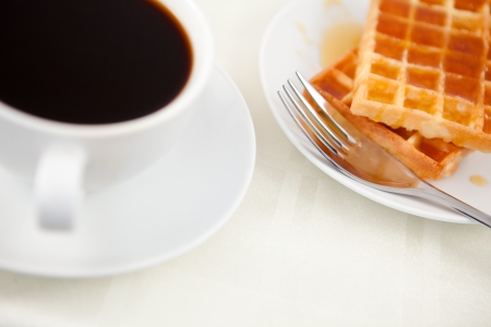 Waffles placed next to a coffee cup on a tableの写真素材