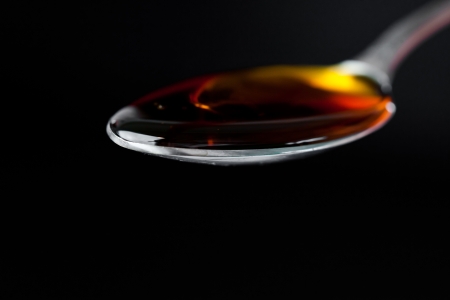 Full honey spoon against a black backgroundの写真素材