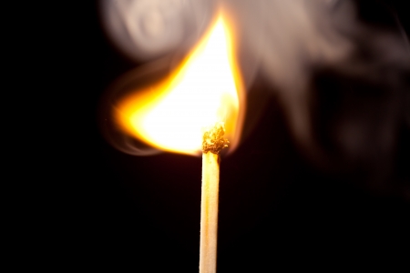 Match set on fire against a black backgroundの写真素材