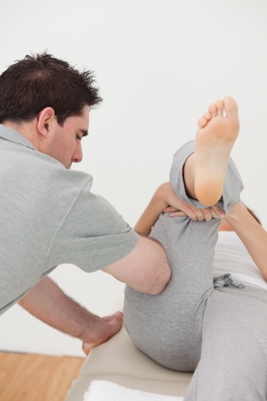 Chiropractor massaging the leg of a woman in a roomの写真素材