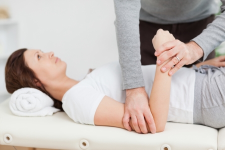 Physiotherapist manipulating the arm of a peaceful woman in a roomの写真素材
