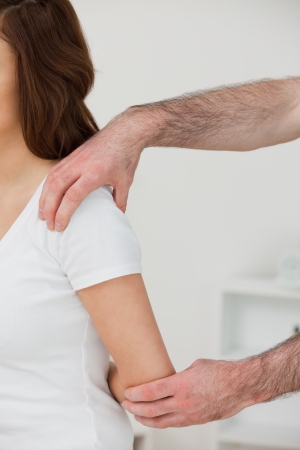 Close-up of a doctor examining the shoulder of a patient in a roomの写真素材