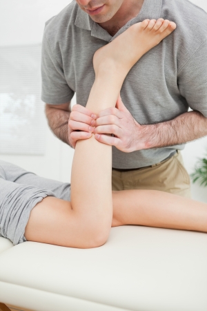 Close-up of a man massaging the leg of a woman in a roomの写真素材