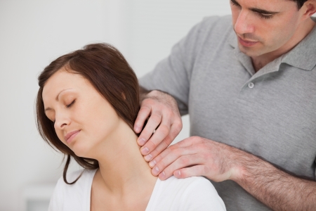 Man massaging the neck of his patient in a medical roomの写真素材
