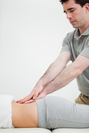 Close-up of a masseur massaging the back of a woman in a roomの写真素材