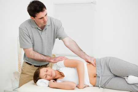 Serious practitioner massaging a peaceful woman in his medical roomの写真素材