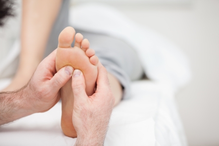 Foot being massaged on a medical table in a roomの写真素材