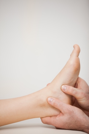 Two thumbs being placed on the side of a foot in a medical roomの写真素材