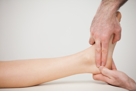 Chiropodist placing two fingers on a foot indoorsの写真素材