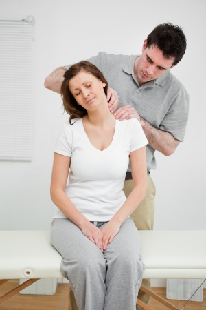 Peaceful woman having a painful neck in a medical officeの写真素材
