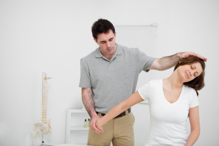 Osteopath stretching the arm of a woman in a medical roomの写真素材