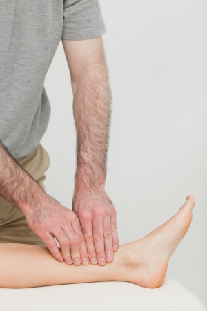 Fingertips massaging a shin bone in a roomの写真素材