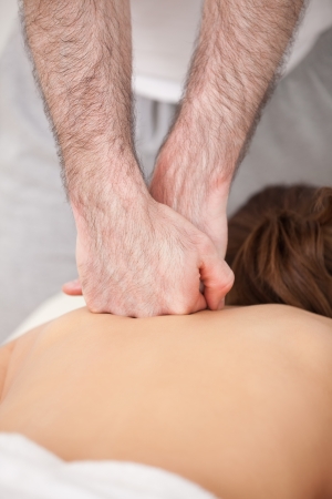 Doctor massaging the back of his patient while using the back of his hand in a roomの写真素材