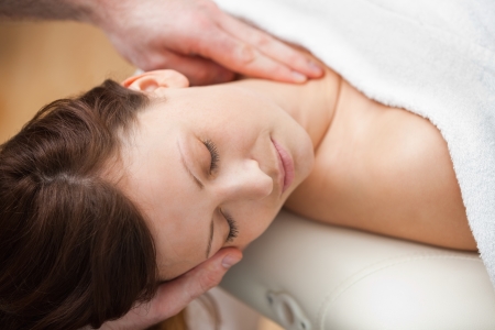 Doctor holding the head of a woman while massaging her neck in a roomの写真素材