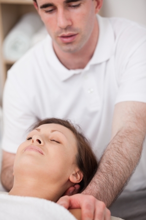Physiotherapist manipulating the neck of his patient in a roomの写真素材
