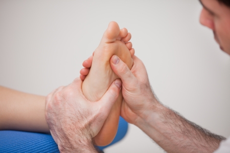 Podiatrist practicing reflexology on the foot of woman in a roomの写真素材