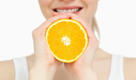 Close up of a woman holding an orange against white backgroundの写真素材