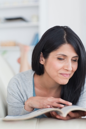 Woman laughing as she holds and touches a book in a living roomの写真素材