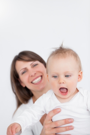 Happy woman playing with her baby against a grey backgroundの写真素材