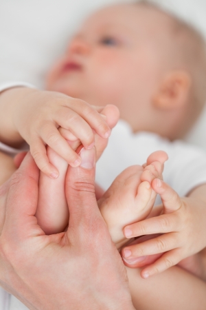Hands touching the feet of a baby against a grey backgroundの写真素材