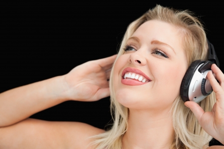 Cheerful blonde woman wearing headphones against a black backgroundの写真素材