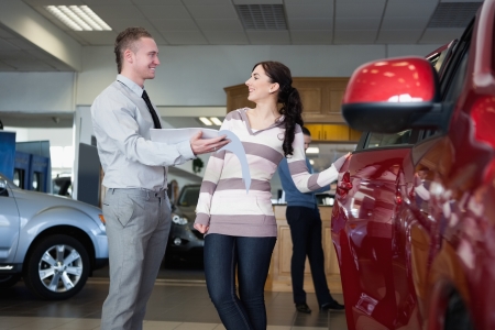Smiling salesman talking with a woman in a car shopの写真素材