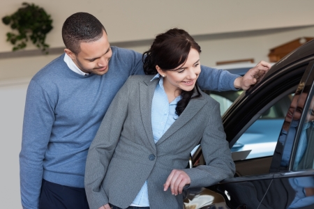Smiling couple looking inside a car in a car shopの写真素材