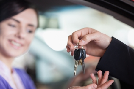 Woman in a car receiving keys from a car dealerの写真素材