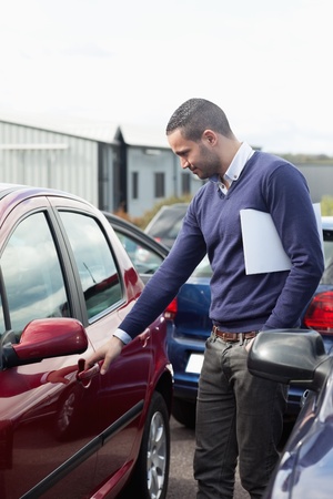 Man looking at a car door while opening it outdoorsの写真素材