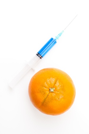 Orange next to a syringe against a white backgroundの写真素材
