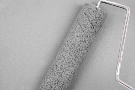Grey background with a paint roller in the middleの写真素材