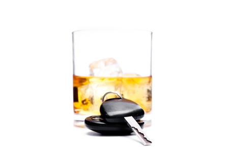 Car key in front of a glass of whiskey against a white backgroundの写真素材