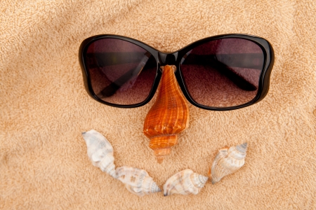 Shellfishes and sunglasses representing a face against a towelの写真素材