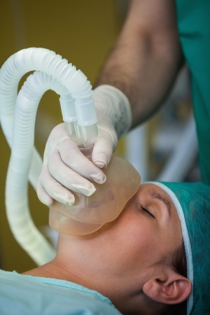 Surgeon placing a mask in the face of a patient in a surgical roomの写真素材