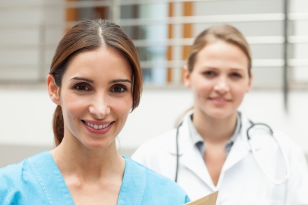 Smiling nurse and doctor standing in a hospital receptionの写真素材